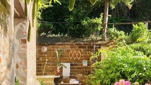 A rustic stone pathway leading to a brick wall with a small table and potted plants. - Ephemeral - Relaxing Retreat (Abruzzo)