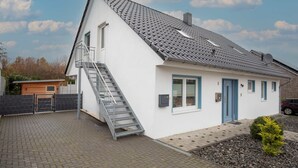 A single-story house with a grey tiled roof, a white exterior, and a blue door. - Vacation apartment Peters Goslar, Sudmerberg 85 sqm (Goslar)