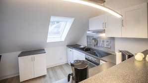 A modern kitchen with white cabinets, a built-in oven, and a window providing natural light. - Vacation apartment Peters Goslar, Sudmerberg 85 sqm (Goslar)