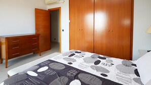 Un dormitorio con cama, armario de madera, cómoda y aire acondicionado.