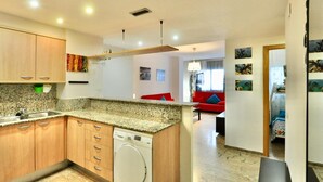 Una cocina funcional con encimeras de granito, armarios de madera y lavadora integrada.