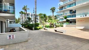 Un moderno complejo de apartamentos con balcones, mobiliario exterior y palmeras.