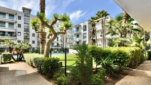 Un patio con palmeras, una piscina y edificios modernos al fondo.
