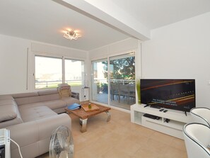 A modern living room with a sofa, a coffee table, a TV, and a fan.