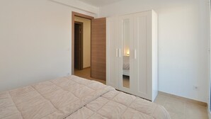 A bedroom with a bed, a wardrobe, and a door leading to another room.