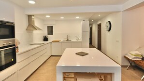 A modern kitchen with white cabinetry, a central island, and a built-in oven.