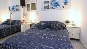 A bedroom with a large bed, a bedside table with a lamp, a mirror, and artwork on the wall.