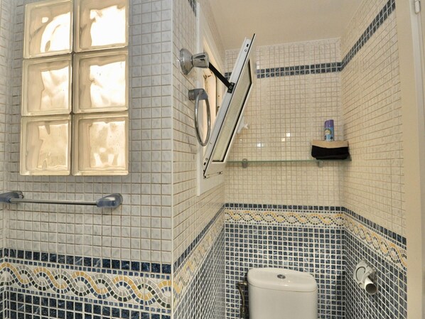 Un baño con inodoro, ducha y ventana.