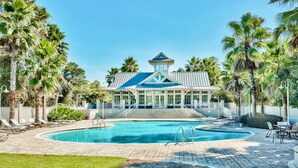 A resort with a swimming pool, lounge chairs, and palm trees.