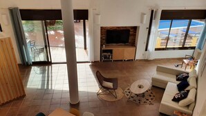 A spacious living area with a sofa, coffee table, and TV, large windows, and a sliding glass door leading to an outdoor area. - Spacious Villa with Private Pool & BBQ, Near Lloret de Mar (Lloret de Mar)