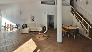 A spacious living area with a sofa, chairs, a dining table, and a staircase. - Spacious Villa with Private Pool & BBQ, Near Lloret de Mar (Lloret de Mar)