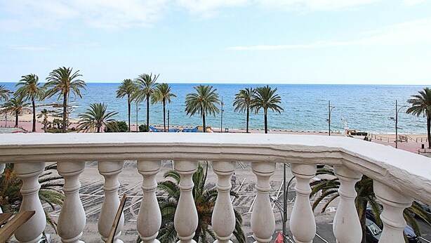 A balcony with a view of the sea and palm trees.