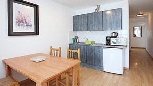 A compact kitchen with grey cabinets, a white dishwasher, and a wooden dining table with chairs.
