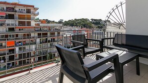 Un balcón con mobiliario exterior y vista a un edificio de varios pisos.