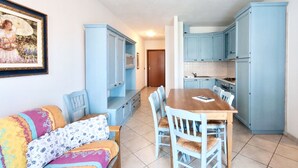 A compact living space with a dining area, kitchenette, and a sofa with patterned cushions.
