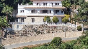 A multi-story building with a stone facade, balconies, and a solar panel on the roof.