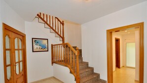 A staircase with wooden balusters and granite steps, leading to a landing with a framed painting.