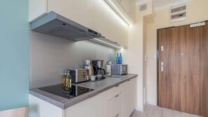 A modern kitchen with a built-in stove, microwave, and coffee maker. - Comfortable Studio | Parking, Balcony, Close to the Beach (Miedzyzdroje)
