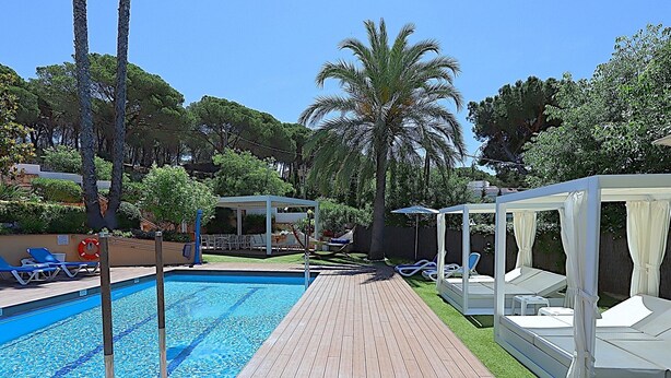 A swimming pool with a wooden deck, lounge chairs, and a covered seating area. - 6-Bedroom Villa with Private Pool in Lloret de Mar (Lloret de Mar)