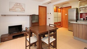 A modern kitchen with a built-in refrigerator, wooden cabinets, and a dining area with a table and chairs. - Cozy Apartment with A/C, 150m from Lloret de Mar Beach (Lloret de Mar)