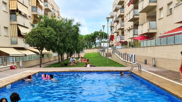 Ein Pool, umgeben von Wohngebäuden, mit Menschen, die schwimmen und entspannen.