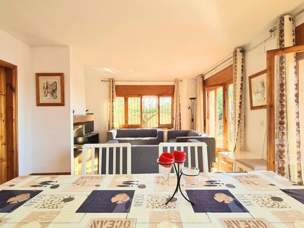 Una sala acogedora con un sofá, una mesa con colcha y un televisor.
