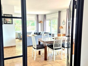 Un área de comedor con una mesa, sillas, un sofá y una lámpara.