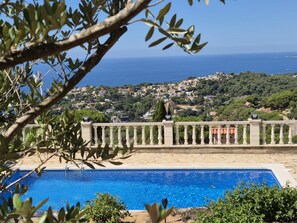 Una piscina con vistas a un pueblo costero y una colina con casas.