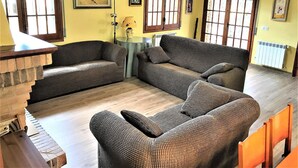 A living room with two sofas, a small table, and a lamp. There are windows with wooden frames and a radiator on the wall. - Modern villa 1 km from beach with private pool and sea views (Lloret de Mar)