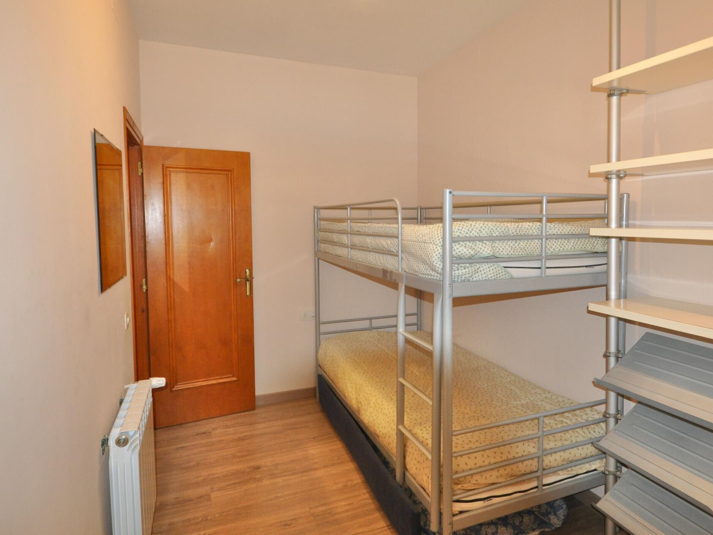 A room with bunk beds, a wooden door, and a radiator.