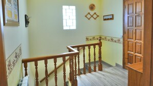 A staircase with wooden balusters and a handrail, leading to a landing with a wooden door and a small window with a brick pattern. - Modern villa 1 km from beach with private pool and sea views (Lloret de Mar)