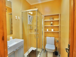 A bathroom with a glass-enclosed shower, a toilet, and a sink.