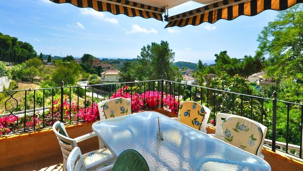 A balcony with a table and chairs, a railing, and a view of the landscape. - Modern villa 1 km from beach with private pool and sea views (Lloret de Mar)