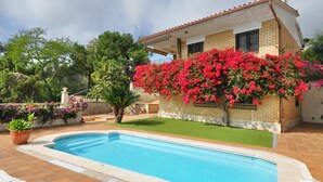 A house with a swimming pool, a garden with various plants, and a brick wall. - Modern villa 1 km from beach with private pool and sea views (Lloret de Mar)