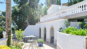 A courtyard with a white building, outdoor seating, and greenery.
