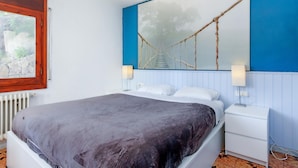 A bedroom with a bed, bedside tables, a window, and a wall-mounted artwork.