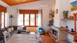A cozy living room with a sofa, a coffee table, a blue bean bag, a fireplace, and a bookshelf.