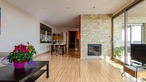 Ein modernes Wohnzimmer mit Kamin, Holzboden und einem Essbereich mit Tisch und Stühlen.