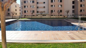 Zwembad met betegeld zonnedek, omringd door appartementencomplexen.
