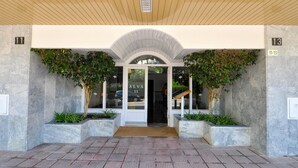 A modern building entrance with a tiled ground, a wooden ceiling, and a sign indicating room numbers 11-13. - Cozy New Apartment, Beach 150m, Internet, A/C, Pool Access, Lloret de Mar (Lloret de Mar)