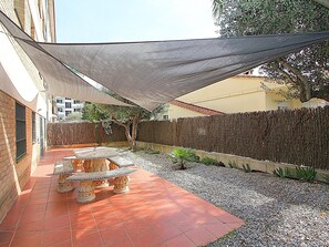 Eine Terrasse mit Tisch und Stühlen, einem schattigen Bereich und einer Zierwand.