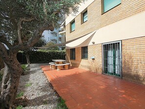 Ein Innenhof mit gefliestem Patio, einem Tisch und Stühlen, einem Baum und einem Gebäude mit Backsteinfassade und Fenster.