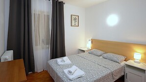 A hotel room with a bed, a nightstand, a lamp, a ceiling fan, and a window with curtains. - 2-BR Apartment, 4-6 people, Lloret de Mar center, WiFi, close to beach (Lloret de Mar)