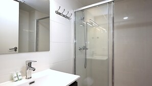 A modern bathroom with a glass-enclosed shower, a white sink with a mirror above it, and a towel rack on the wall. - 2-BR Apartment, 4-6 people, Lloret de Mar center, WiFi, close to beach (Lloret de Mar)