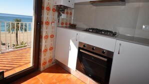 A kitchen with a gas stove, oven, and a view of the beach through a glass door. - 2-BR Apartment, 4-6 people, Lloret de Mar center, WiFi, close to beach (Lloret de Mar)