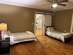 A room with two beds, wooden flooring, a ceiling fan, and a door leading to another room. - Located 3 miles to Grenada Lake  (Grenada)