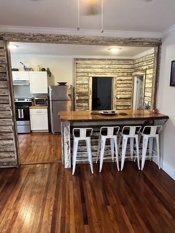 A kitchen with a wooden island, white bar stools, and a view into the adjacent room. - Located 3 miles to Grenada Lake (Grenada)