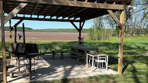 Un espace extérieur abrité comprenant un barbecue, une table de pique-nique et des chaises.