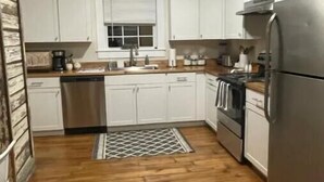 Une cuisine de taille réduite avec des meubles blancs, des appareils en acier inoxydable et un plancher en bois.