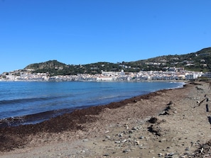 A coastal town with a rocky beach and buildings along the water.
